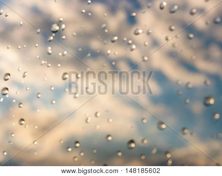 Blurred water drops of rain on blue glass with bokhe as background. Blurred rain drops on window