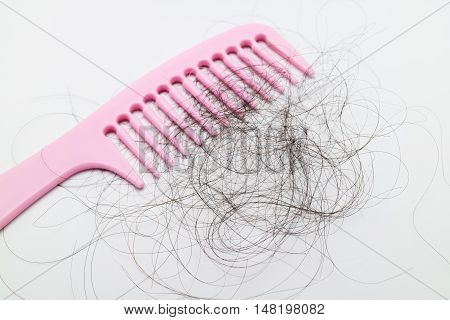 Pink comb with lots of hair fall on white background. Hair loss problem in woman. Postpartum defluvium.