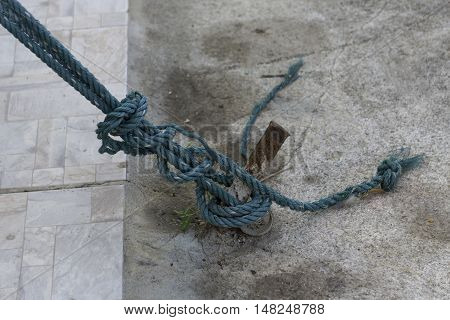 nylon rope tied on steel rod with concrete floor background.