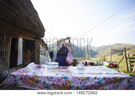 Salciua, Romania - September 14, 2016: Old rural woman selling cheese at the farm in the mountains