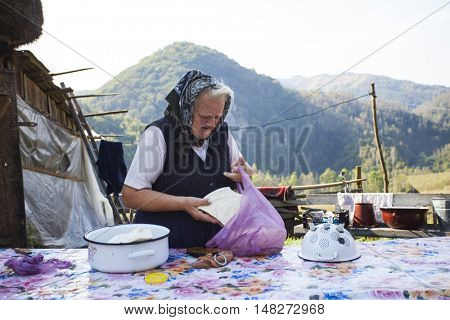 Salciua, Romania - September 14, 2016: Old rural woman selling cheese at the farm in the mountains
