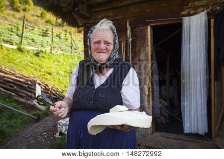 Salciua, Romania - September 14, 2016: Old rural woman selling cheese at the farm in the mountains