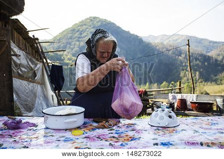 Salciua, Romania - September 14, 2016: Old rural woman selling cheese at the farm in the mountains