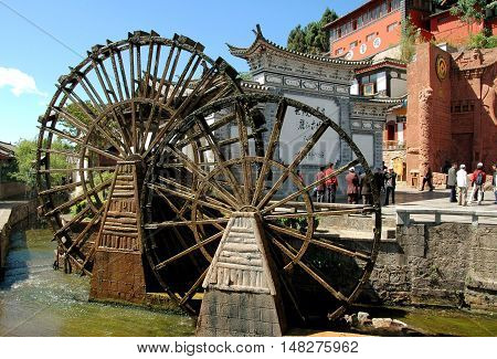 Lijiang China - April 19 2006: Two traditional Chinese wooden water wheels built on a stream flowing through Si Feng Square