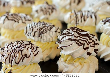 Desserts with white meringue. Dark chocolate and cream. Sugar mixed with egg whites. Tasty sweets in french cafe.