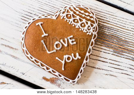 Cookie with inscription. Brown biscuit on wooden surface. Convey an important message. Dessert that tastes like love.