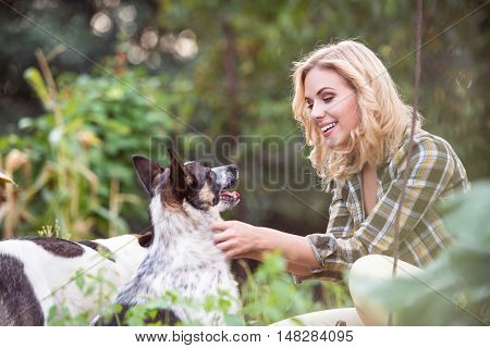 Beautiful blond woman with her dog in green garden