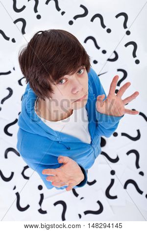 Teenager has no clue - standing on question marks with a lost expression