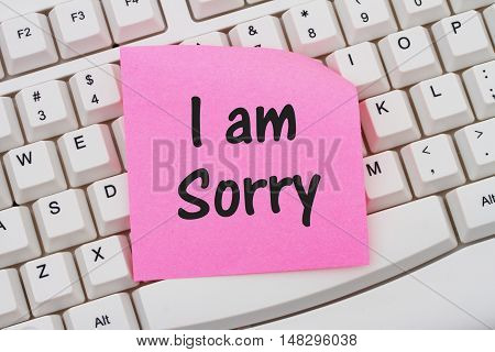 A close-up of a keyboard with pink sticky note with text I am Sorry