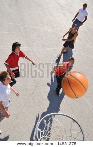 gorup de rapazes que jogar basquete ao ar livre na rua, com longas sombras e bird Ver os psicoló