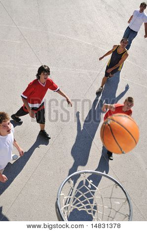 gorup de rapazes que jogar basquete ao ar livre na rua, com longas sombras e bird Ver os psicoló