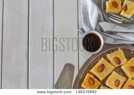 Homemade Basbousa with Coffee on White Wooden Table Horizontal with Copy Space from Above