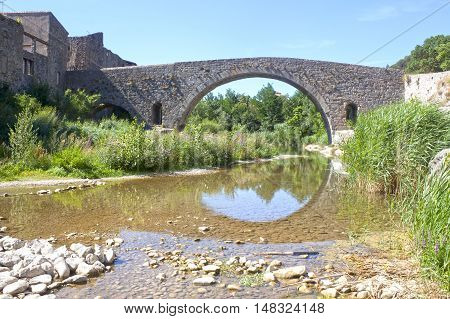 Vieux Bridge In Lagrasse And The Reflection In The River Making A Circle, France