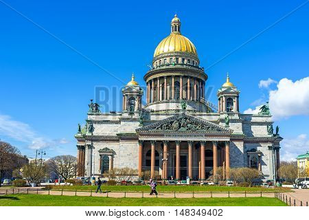 SAINT PETERSBURG RUSSIA - APRIL 25 2015: The facade of Neoclassical St Isaac's Cathedral the dome covered with pure gold numerous bronze sculptures and red granite columns decorate Basilica on April 25 in Saint Petersburg.