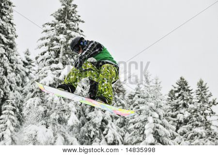 jungen springen in Luft ind zeigt Trick mit dem Snowboard auf Wintersaison