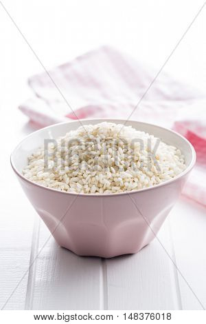 Arborio rice in bowl on white table.