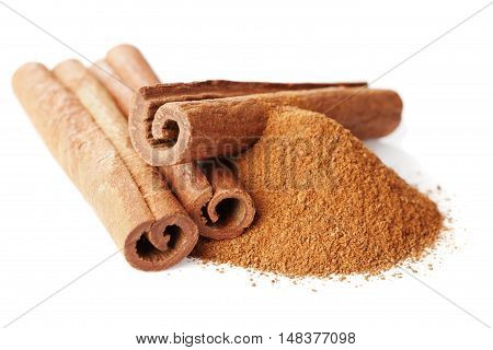 Closeup of cinnamon sticks and powder of ground cinnamon on white background.