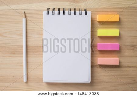 Topview of office stuff on wooden working table. Mock up. Note paper white blank notebook post-it note pencil.