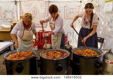 Budapest Hungary - 20 August 2016: Women dressed in traditional hungarian costumes cooking goulash at the fair during the celebration of the St. Stephen's Day.