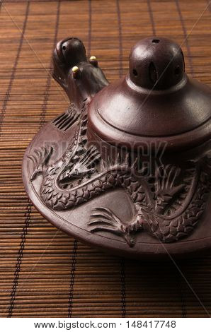 brown Chinese teapot of Yixing clay with traditional ornament on bamboo Mat