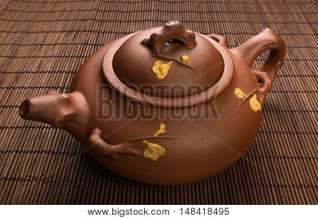brown Chinese teapot of Yixing clay with traditional ornament on bamboo Mat