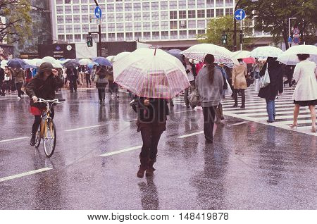 TOKYO - APRIL 23: people crossing the street in Tokyo Shibuya district under rain on April 23 2011 in Tokyo Japan. Shibuya district is very famous for it's fashion shops and crowds of young people.