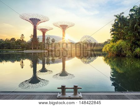 Singapore, Republic of Singapore - May 5, 2016: Supertree grove and Cloud garden greenhouse reflecting in pond at sunrise