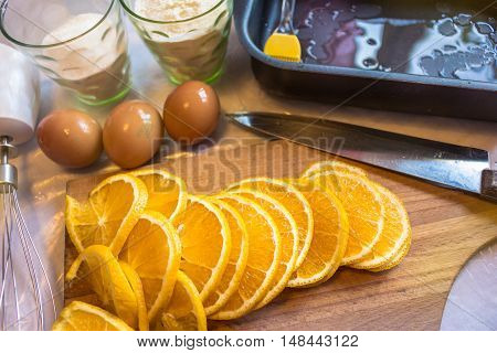 Cooking in the kitchen, a wooden board with a knife, sliced orange, flour in a glass