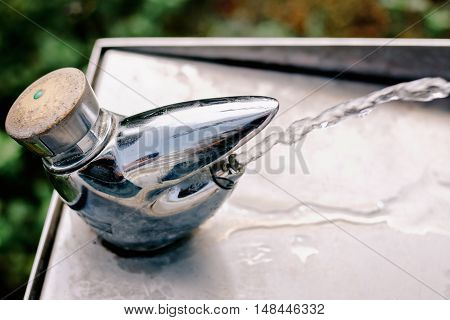 Clean drinking water flowing from a metal faucet - vintage tone film effect (selective focus)