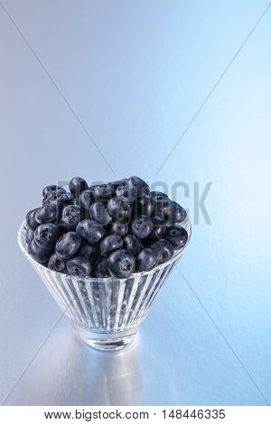 Blueberry in a crystal bowl on a silver background. It is useful for vision.