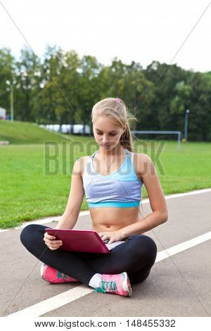 beautiful girl working on laptop, man reads a book at the stadium