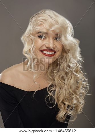 curly cute young blonde smiling sitting in the studio in a black T-shirt