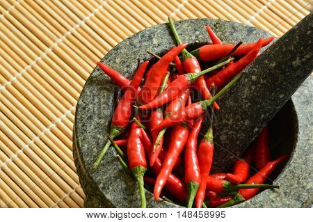 spicy chili in stone mortar on bamboo mat