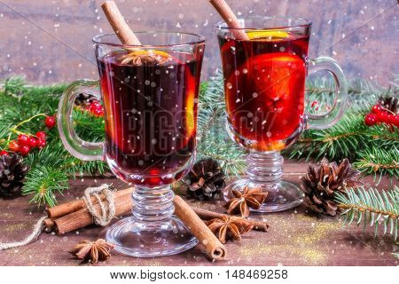 christmas mulled wine with cinnamon sticks anise and orange on wooden table background with fir branches and pine cones