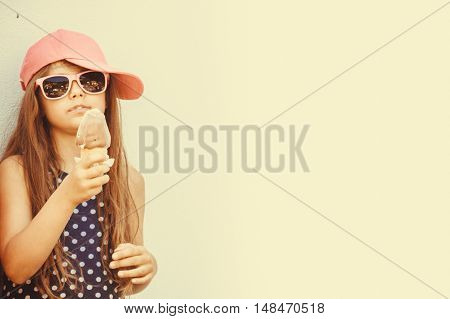 Kid eating gelato soft serve ice cream. Little girl in sunglasses enjoying summer holidays vacation. Instagram filter.