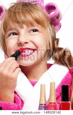 Adorable little girl playing with mommy's make up. Happy kid painting her lips. Fashion little child applying make-up on white background.