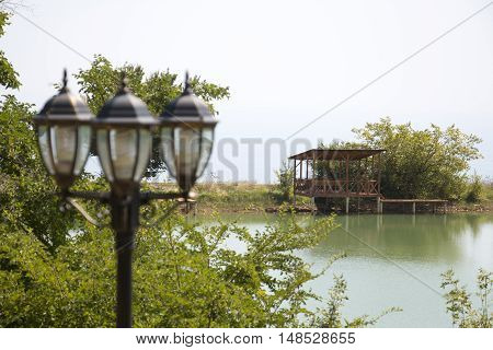 Gazebo on the shore of the pond in the background of a lamppost