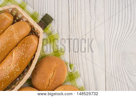 Buns in a wicker basket on old wooden table. Top view.