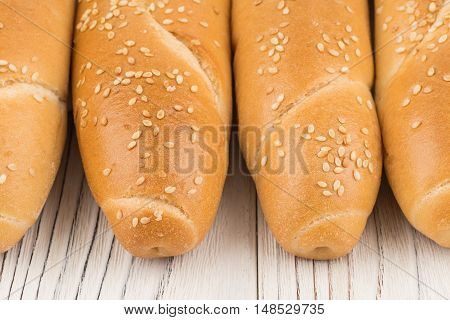 Bun with sesame seeds on old white wooden table. Selective focus.