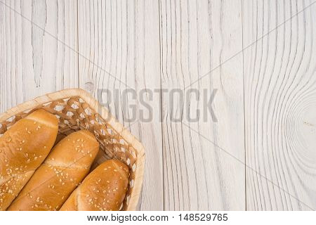 Buns in a wicker basket on old wooden table. Top view.