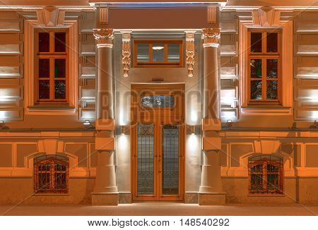 Several windows in a row and door on night illuminated facade of urban office building front view St. Petersburg Russia