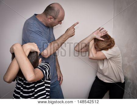 Domestic violence: Young boy bending down and covering his head with his hands while the father is threatening his mother. Focus on the young boy.