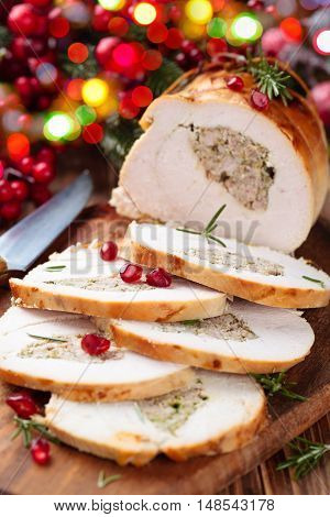 Stuffed turkey breast with pomegranate and rosemary on cutting board.