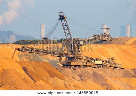 Mining machinery in a brown coal open pit mine. In the background are the power plants.
