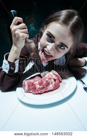 Portrait of a young girl with knife and and a piece of raw meat on a plate. Girl in school uniform as killer. The image in the style of Halloween and Addams family
