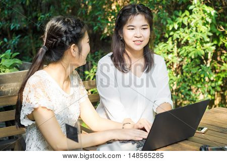 Business asian women discussing business plan on laptop in cafe meeting outdoor garden