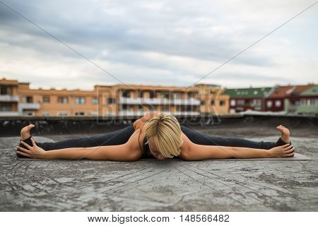 Woman is practicing yoga on the roof,Upavista konasana