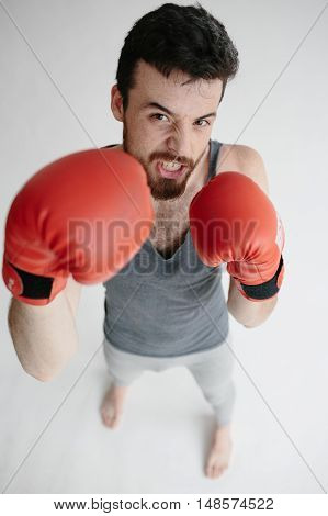 Man standing with a red gloves on a gray background. Male with a beard