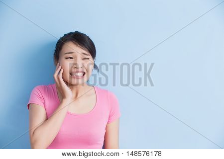 woman have toothache isolatedon blue background asian