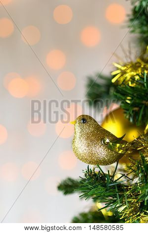 Festive Christmas close up of tree decorated with gold glitter robin tinsel and bauble. Bokeh copy space. Vertical.